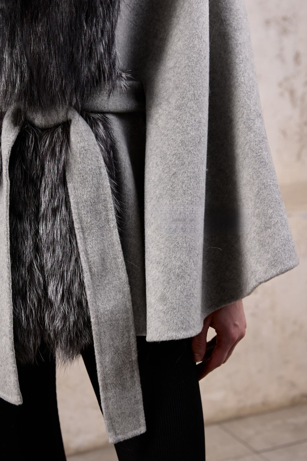 Close up from a stylish cashmere cape with genuine silver fox fur, a woman exudes chic comfort and versatile fashion.