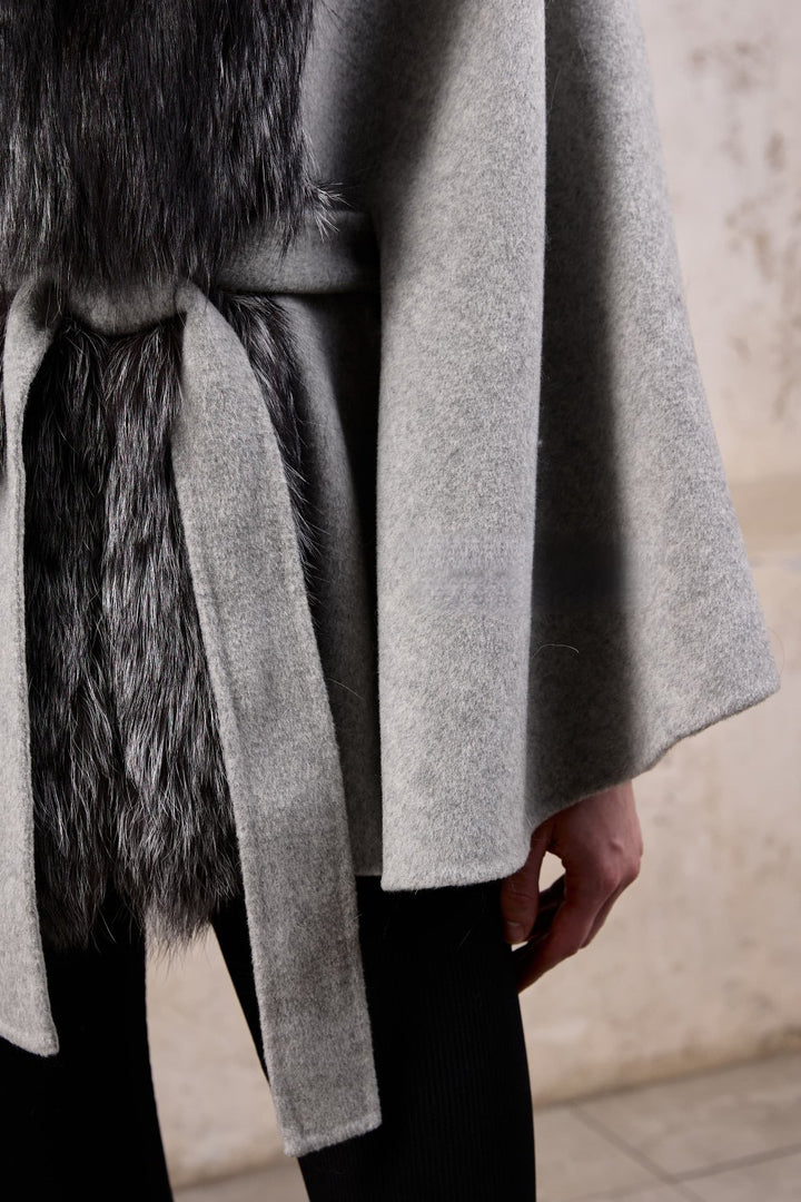 Close up from a stylish cashmere cape with genuine silver fox fur, a woman exudes chic comfort and versatile fashion.