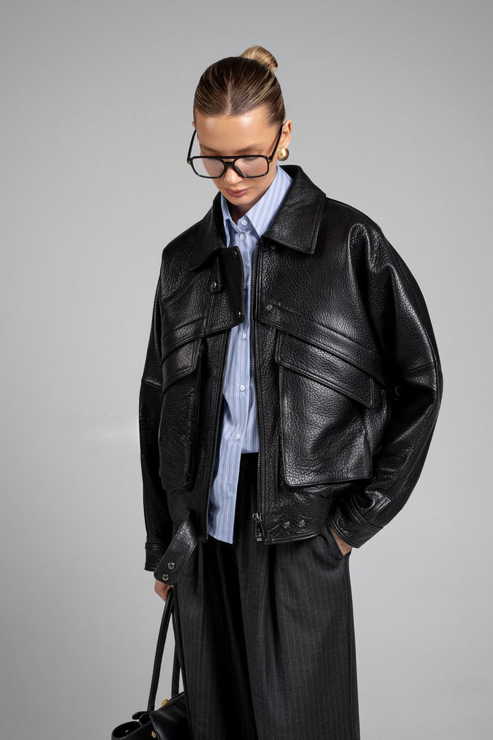Model wearing structured black leather jacket with gold hardware, reflecting modern luxury and sleek design.