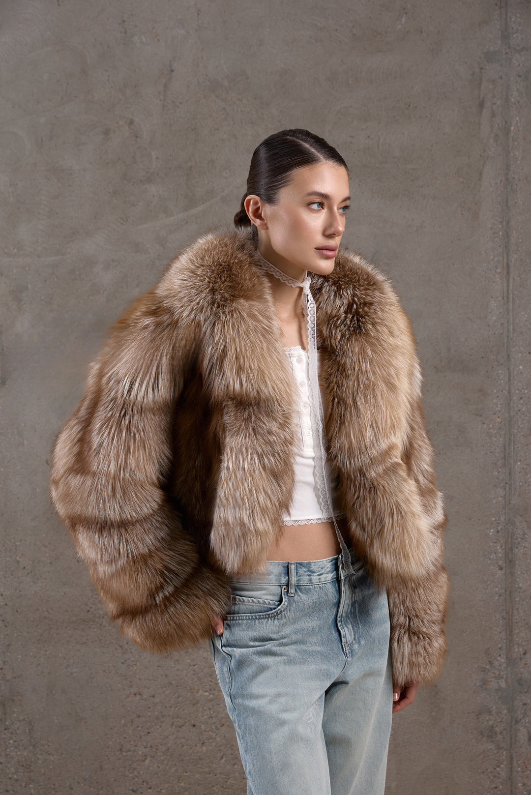 A woman pairs her warm, multidimensional brown fox fur coat with jeans, blending casual comfort with timeless winter elegance.