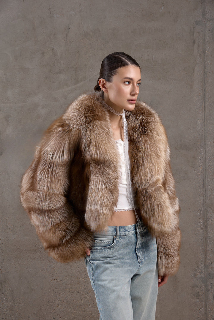 A woman pairs her warm, multidimensional brown fox fur coat with jeans, blending casual comfort with timeless winter elegance.