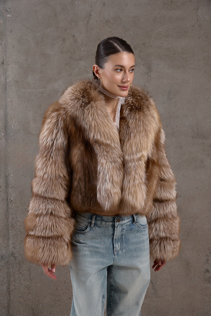 Wearing jeans and a plush short fox fur coat in natural brown shades, the woman radiates refined charm and cold-weather luxury.