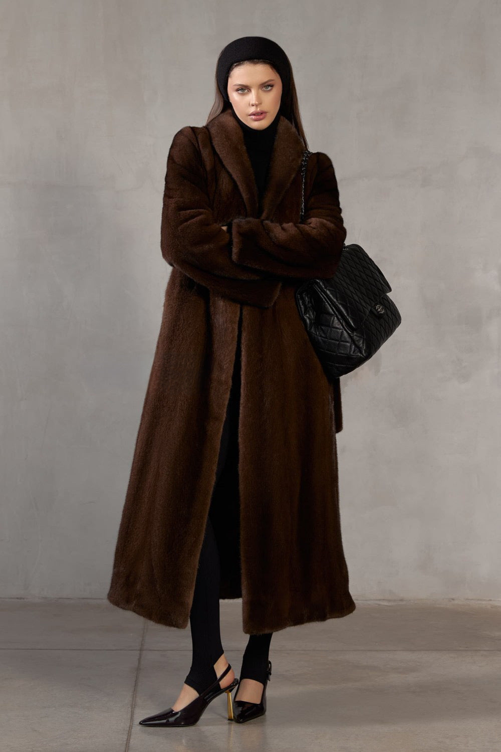 Wrapped in luxurious dark brown mink, a woman showcases timeless sophistication in a gracefully draped long coat.