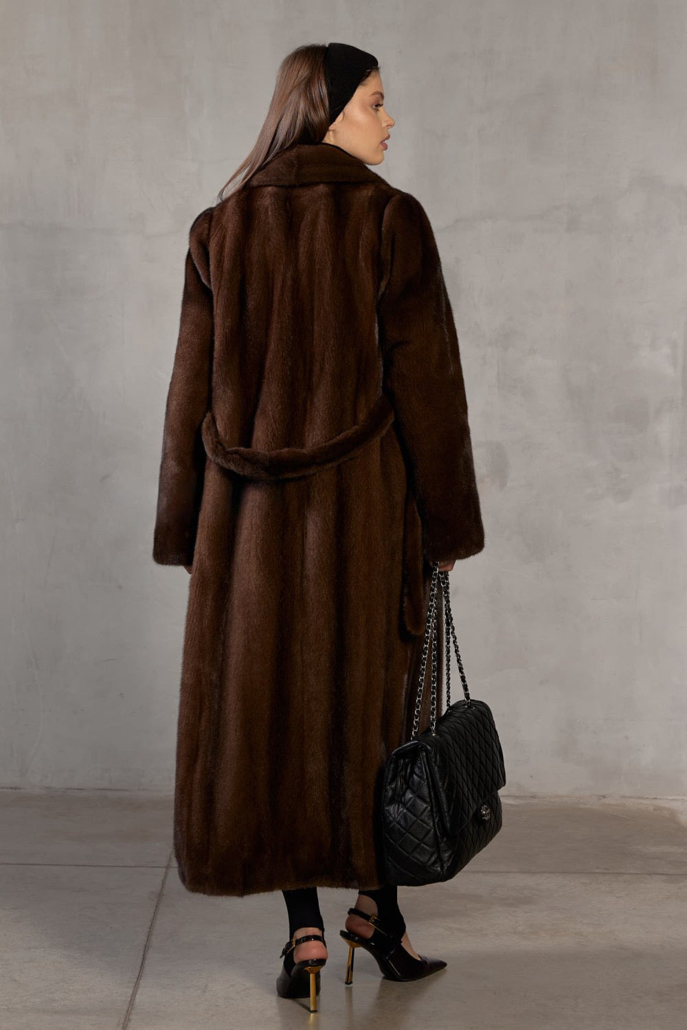 Wearing a sumptuous dark brown mink fur coat, a woman embodies classic glamour with every soft, flowing detail.