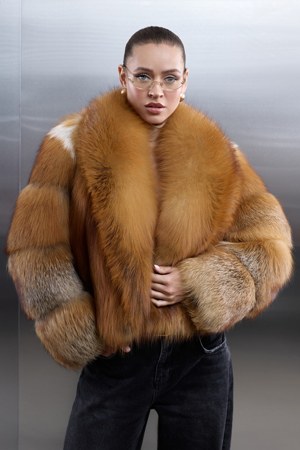 A woman wears a long coat crafted from genuine red fox fur, its thick, plush texture wrapping her in warmth and luxurious winter elegance.
