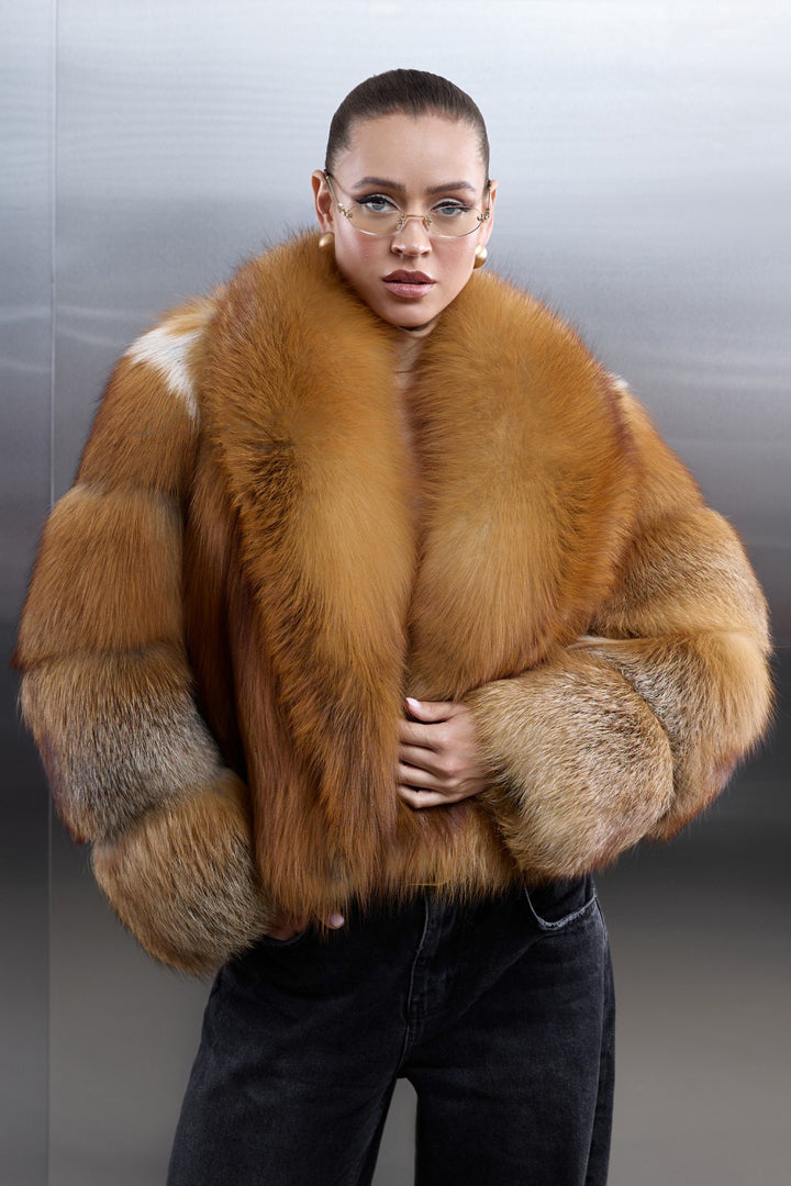 A woman wears a long coat crafted from genuine red fox fur, its thick, plush texture wrapping her in warmth and luxurious winter elegance.