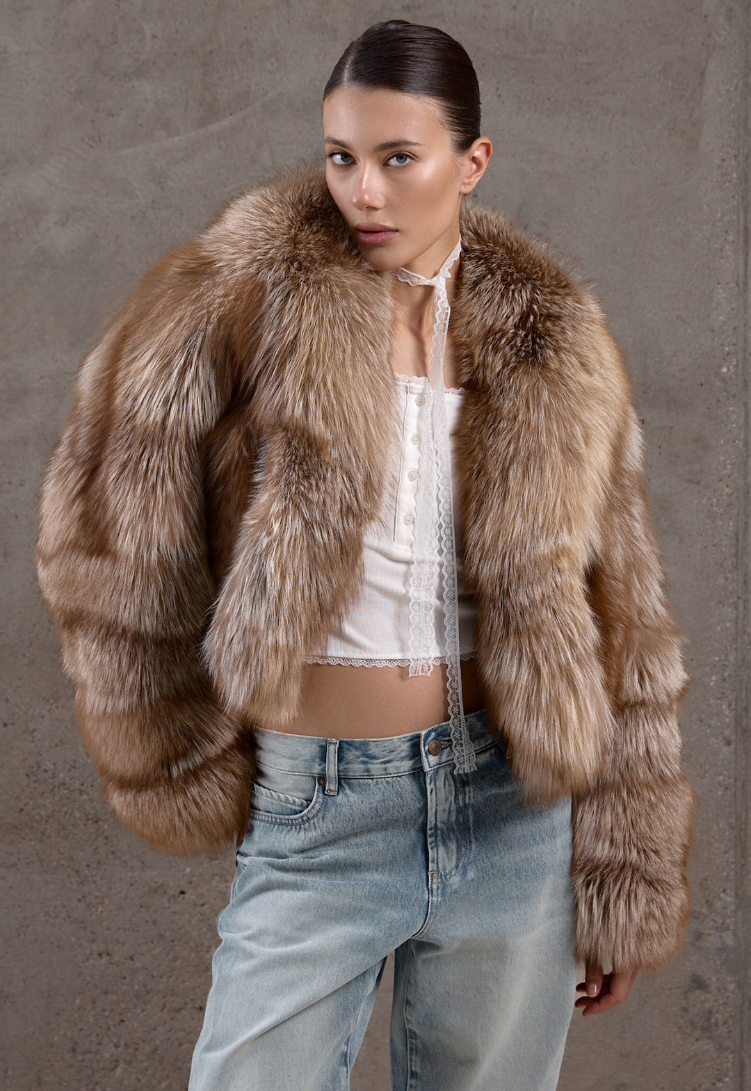 A woman wears a voluminous short fox fur coat in blended brown hues with jeans, exuding warmth and chic winter sophistication.