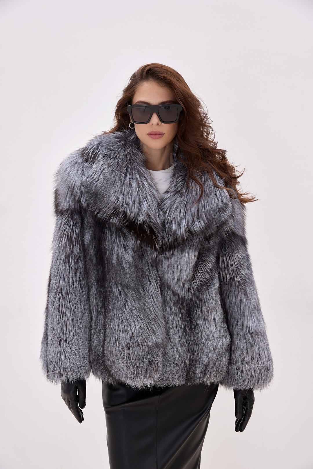 Woman wears a voluminous Silver Fox Fur Coat paired with sleek black leather gloves, showcasing an elegant winter ensemble with full-pelt construction and luxurious texture.
