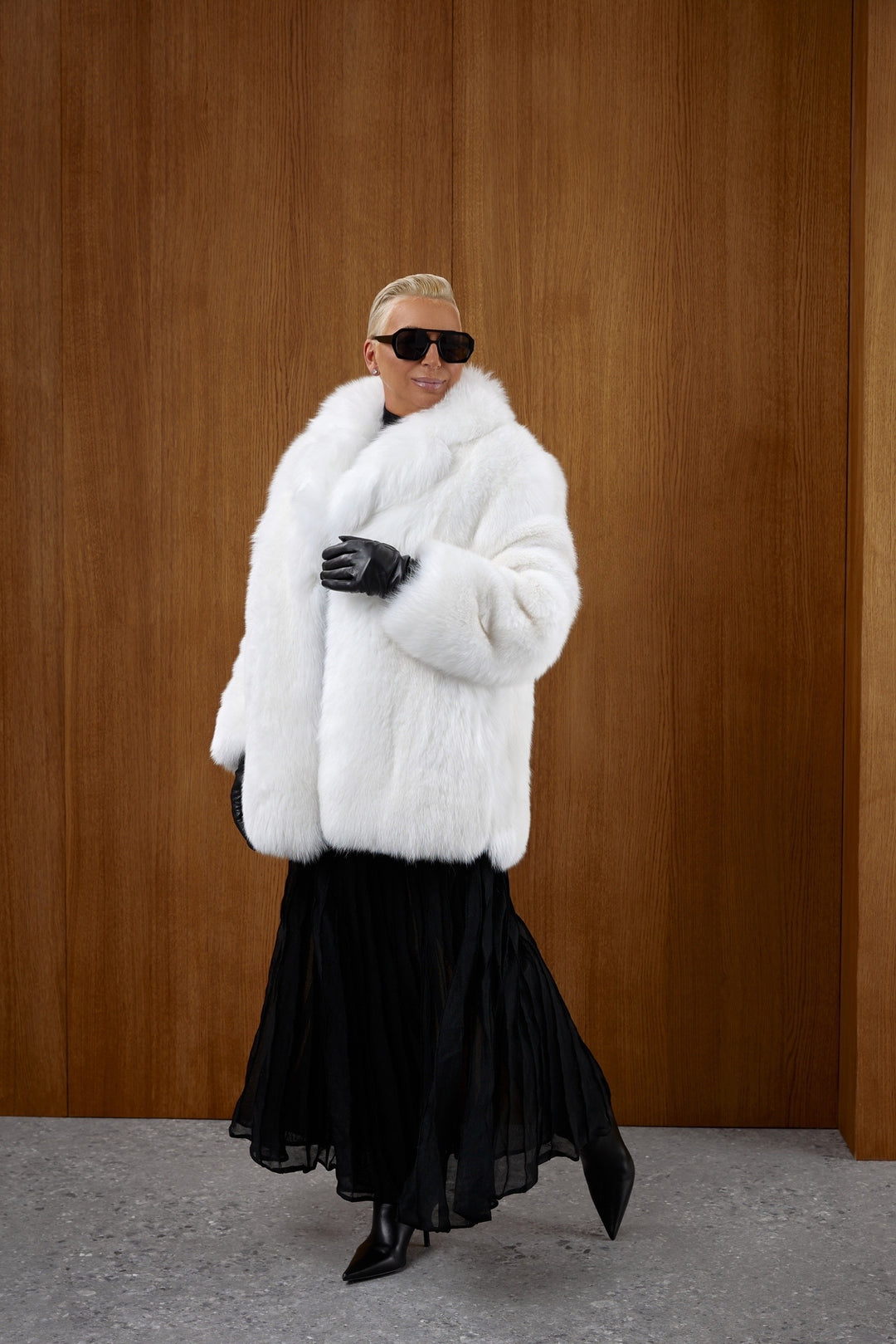A woman wearing a glamorous white midi-length fox fur coat, designed with full fur panels and a tailored shape for warmth and winter elegance.