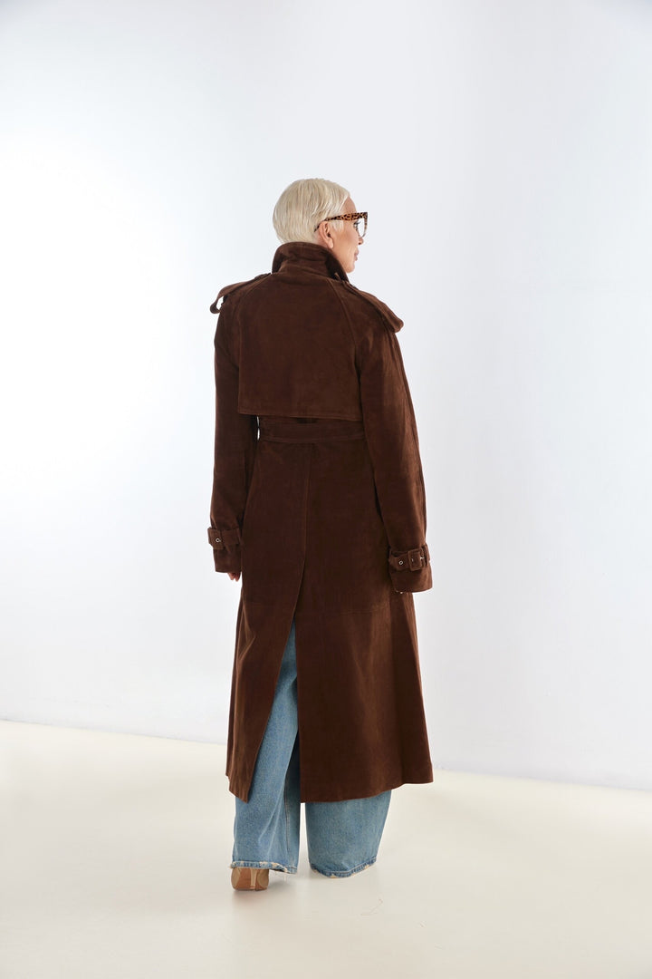 A plus size woman models a chocolate brown suede trench coat, tailored to flatter curvier figures while offering warmth and polished style.