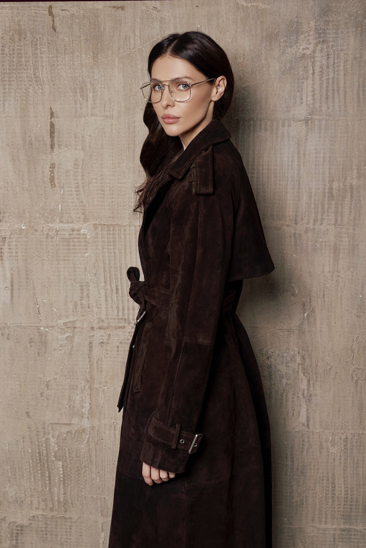 A woman wearing a tailored suede trench coat, designed in a classic double-breasted style and made from soft, premium suede leather.