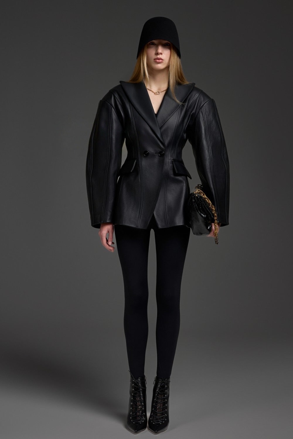 A woman wearing a black leather blazer jacket with a cinched waist, crafted from soft, supple leather for a sleek, feminine silhouette suited for both work and elevated casual style.