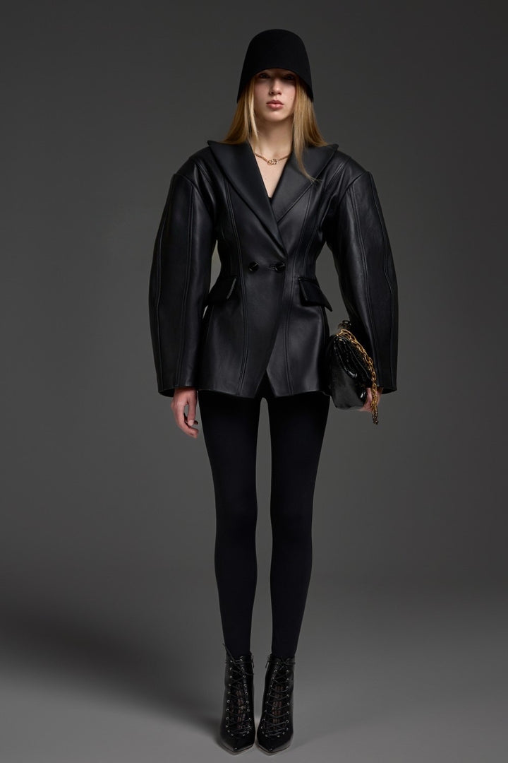 A woman wearing a black leather blazer jacket with a cinched waist, crafted from soft, supple leather for a sleek, feminine silhouette suited for both work and elevated casual style.