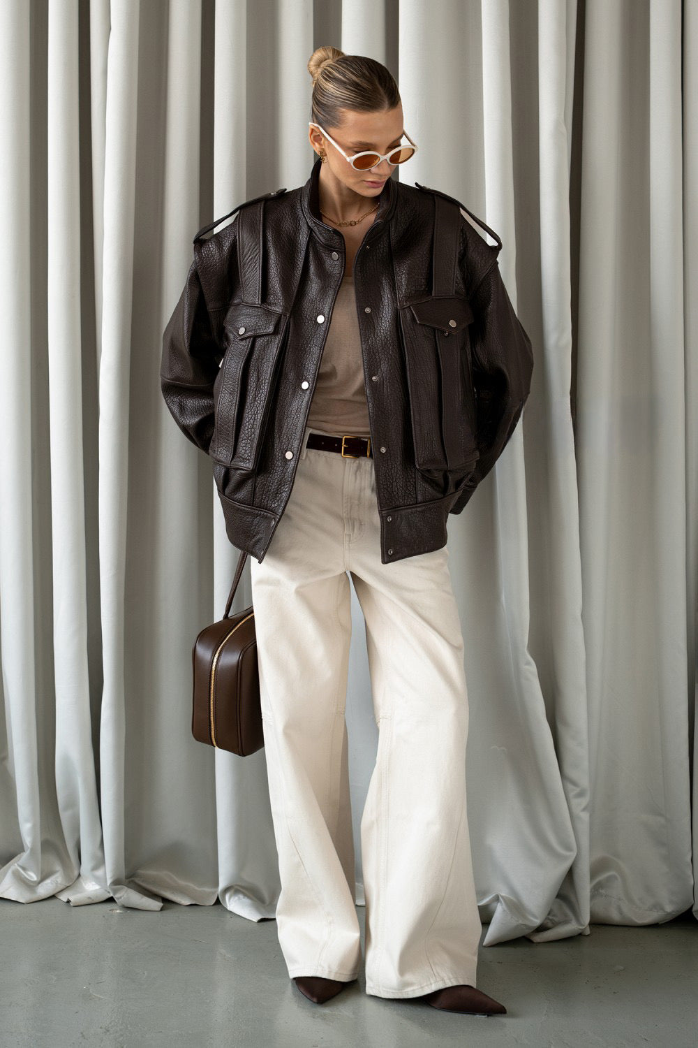Woman in a rich brown leather jacket with a clean silhouette, blending modern edge with casual elegance.