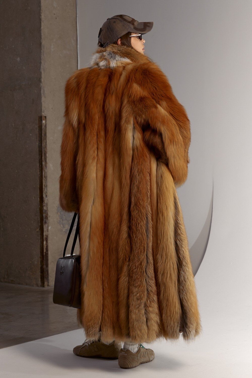 Sporty yet sophisticated, a woman dons a long red fox fur coat that combines lavish warmth with a streamlined silhouette, perfect for urban winter fashion.