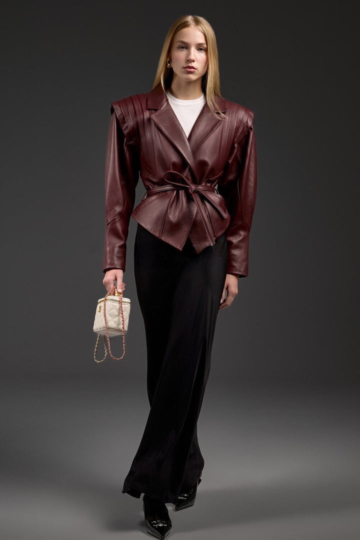 A woman models a luxurious burgundy lambskin leather jacket with a contoured silhouette, combining modern edge with sophisticated style.