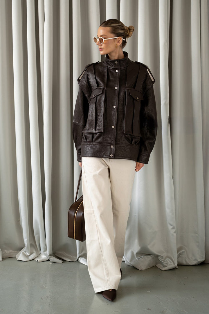 Stylish woman wears a soft, dark brown leather jacket, perfect for effortless layering in both city and relaxed settings.