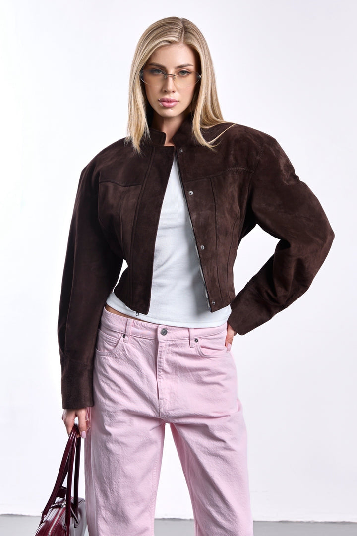 A woman dressed in a premium deep espresso suede jacket, designed with a structured cropped cut, clean lines, and minimalistic elegance.