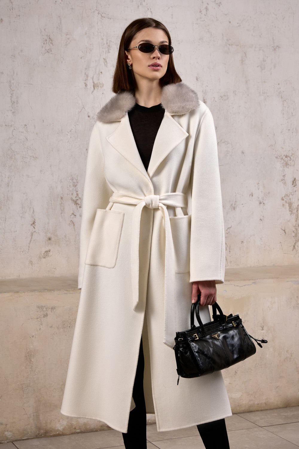 A woman wears a luxurious cashmere coat with a genuine grey mink fur collar, blending timeless elegance with soft texture and a relaxed silhouette.