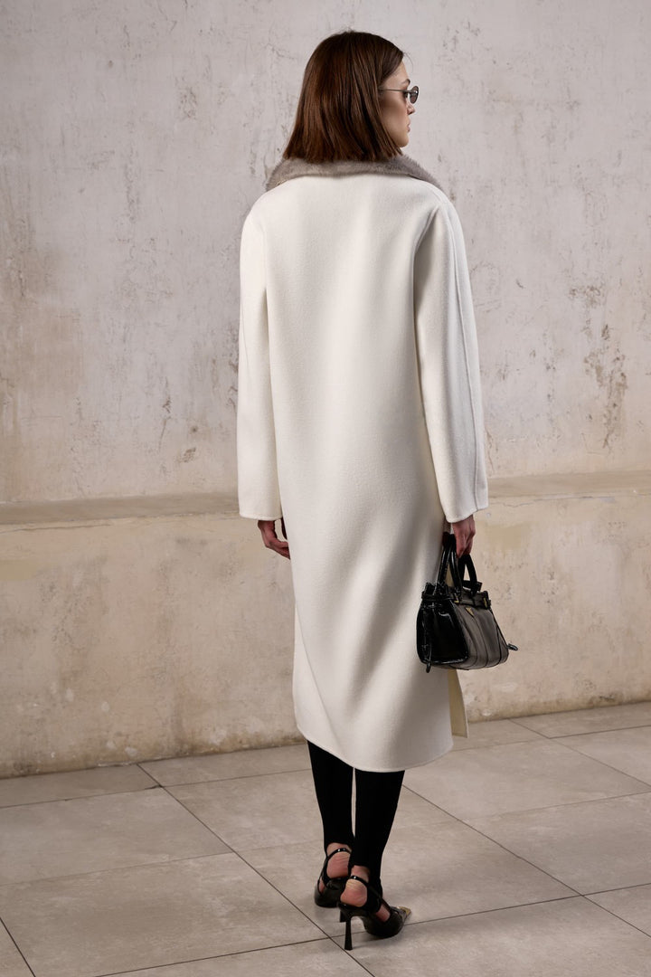Gracefully styled woman wearing a soft cashmere coat with a plush grey mink collar, perfect for elevated cold-weather looks.