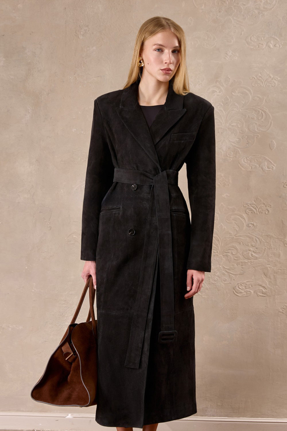 Dressed in an espresso-hued suede coat, a woman exudes confidence with its sculpted silhouette and refined structure.