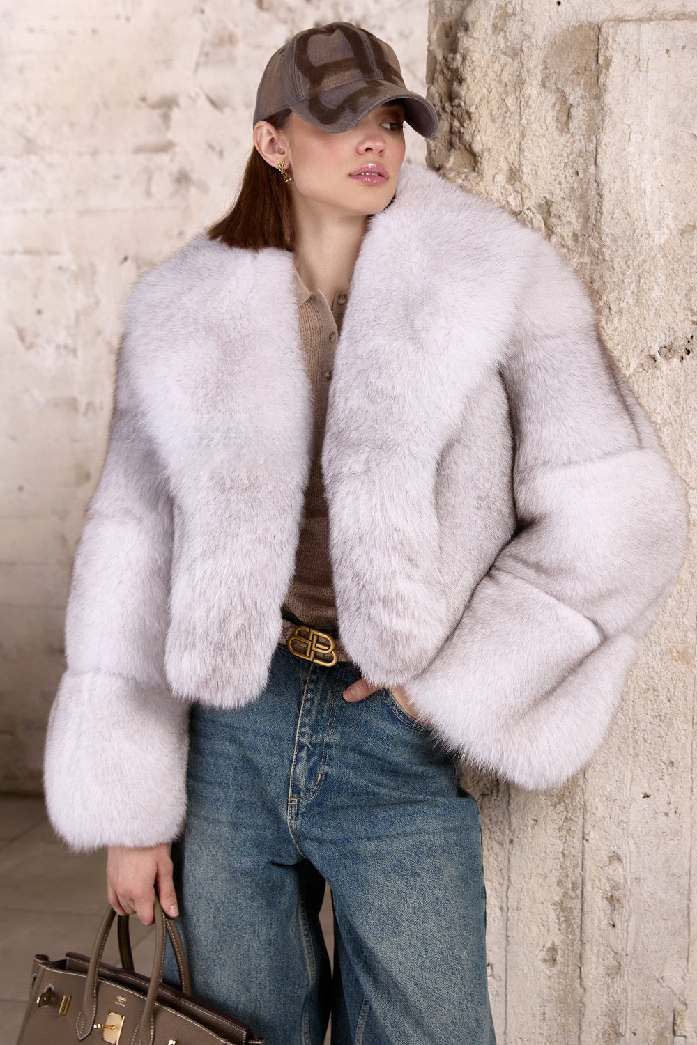 A woman wears an elegant short Fox Fur coat in a rich natural shade, featuring soft, voluminous fur with multidimensional tones for warmth and sophistication.