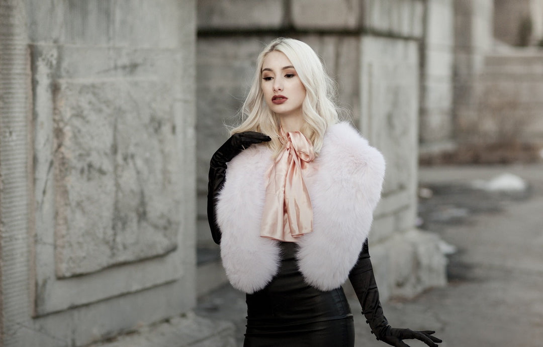 A woman wearing a light pink fox fur collar. 