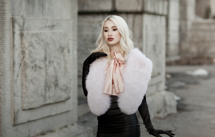 A woman wearing a light pink fox fur collar. 